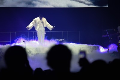 Saucisson sec tranché sur une planche avec des cornichons et des olives, posé sur une table blanche.