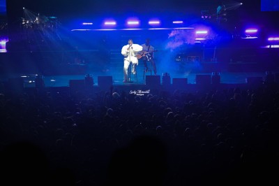 Saucisson sec tranché sur une planche avec des cornichons et des olives, posé sur une table blanche.