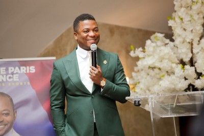 Saucisson sec tranché sur une planche avec des cornichons et des olives, posé sur une table blanche.