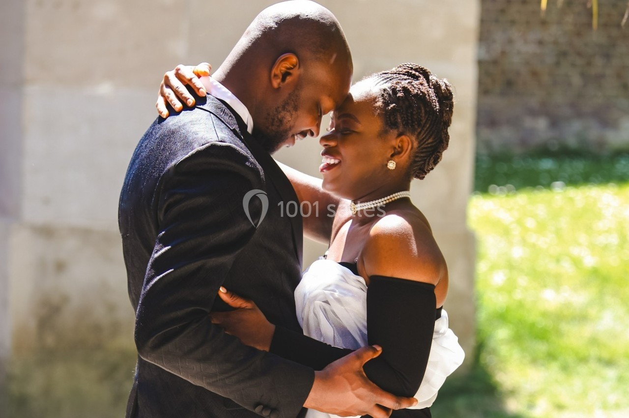 Un couple élégant s'enlace tendrement en extérieur, sous une lumière naturelle.
