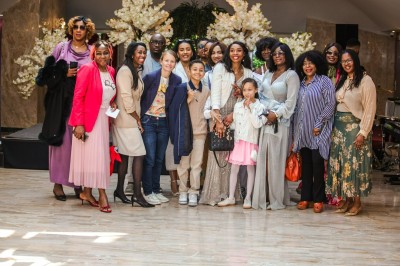 Un groupe de personnes souriantes posant ensemble devant un décor floral lumineux.