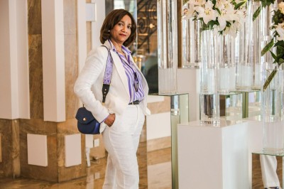 Un groupe de personnes souriantes posant ensemble devant un décor floral lumineux.