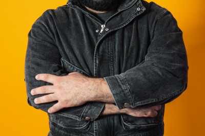 Un chanteur sur scène, vêtu de blanc, levant un bras sous des lumières de spectacle et un écran en arrière-plan.