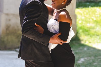 Un chanteur sur scène, vêtu de blanc, levant un bras sous des lumières de spectacle et un écran en arrière-plan.