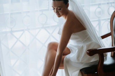 Un chanteur sur scène, vêtu de blanc, levant un bras sous des lumières de spectacle et un écran en arrière-plan.