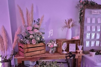 Décoration florale avec roses et pampas sur une table en bois, accompagnée d'un vélo et d'un tableau d'affichage.