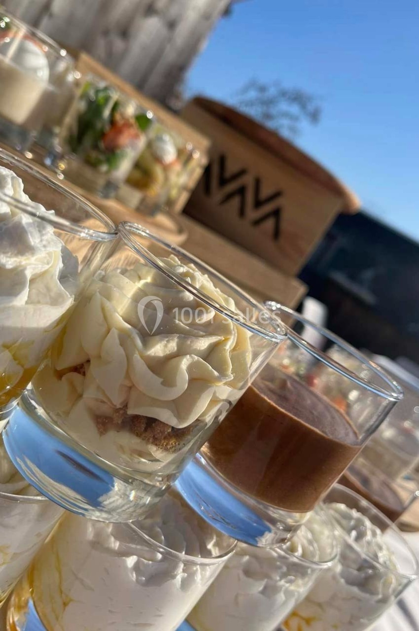 Verrines variées présentées sur une table en extérieur, avec un ciel bleu en arrière-plan.