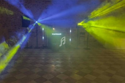 Groupe de personnes dansant sous des lumières bleues dans une ambiance festive en intérieur.