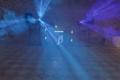 Effets lumineux colorés projetés dans une salle sombre avec un sol carrelé et des murs en pierre.