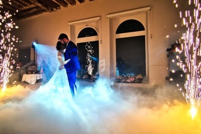 Un couple danse au milieu d'une scène éclairée par des étincelles et entourée de fumée dans une salle élégante.