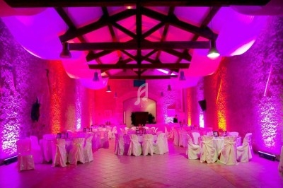 Jeux de lumières colorées projetés dans une salle avec sol en carreaux et murs en pierre.