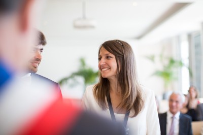 Miniature Hadrien Brunner Photographe #8 Une femme en robe blanche et talons pose son pied sur un ballon de football sur une pelouse.