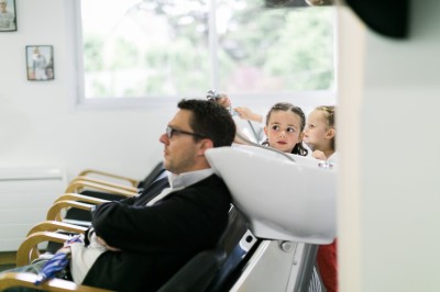 Miniature Hadrien Brunner Photographe #9 Une femme en robe blanche et talons pose son pied sur un ballon de football sur une pelouse.