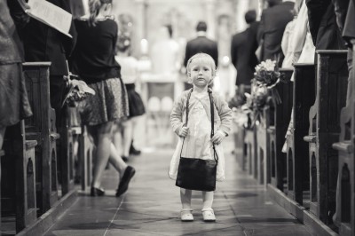 Miniature Hadrien Brunner Photographe #10 Une femme en robe blanche et talons pose son pied sur un ballon de football sur une pelouse.
