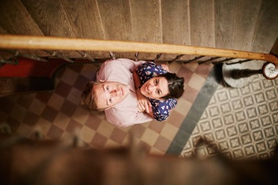 Miniature Hadrien Brunner Photographe #21 Une femme en robe blanche et talons pose son pied sur un ballon de football sur une pelouse.
