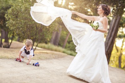 Miniature Hadrien Brunner Photographe #34 Une femme en robe blanche et talons pose son pied sur un ballon de football sur une pelouse.