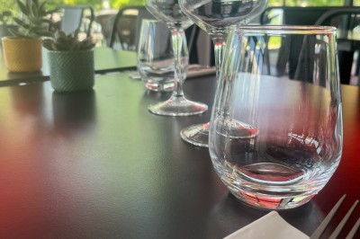 Quatre verres alignés sur une table noire avec des couverts, des plantes décoratives et une vue sur l'extérieur.