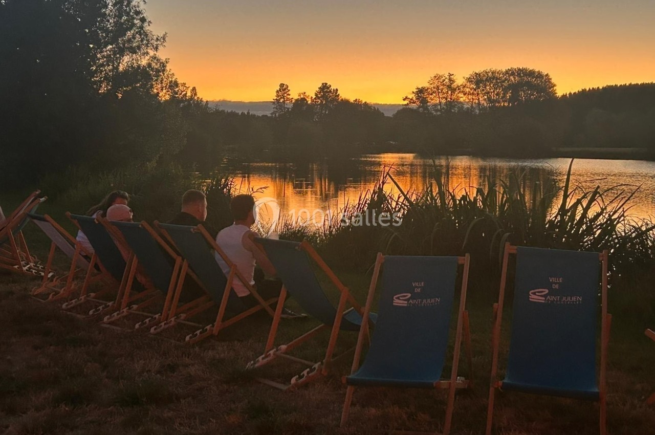 Des personnes assises sur des chaises longues au bord d'un lac, admirant un coucher de soleil.