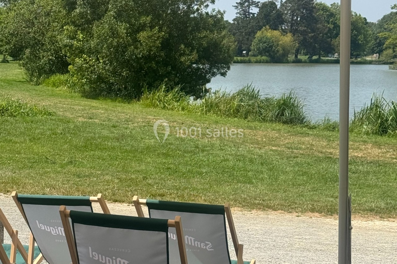 Chaises longues alignées face à un lac entouré de verdure, sous un ciel dégagé.