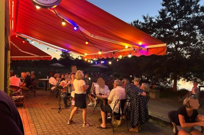 Quatre verres alignés sur une table noire avec des couverts, des plantes décoratives et une vue sur l'extérieur.