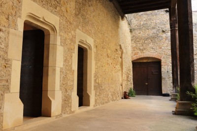 Miniature Location salle Saint-Félix-Lauragais (Haute-Garonne) - La Commanderie #6 Portail métallique noir fermé entre deux murs en pierre, entouré de végétation et d'arbustes.