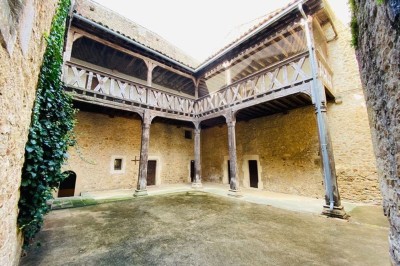 Miniature Location salle Saint-Félix-Lauragais (Haute-Garonne) - La Commanderie #5 Portail métallique noir fermé entre deux murs en pierre, entouré de végétation et d'arbustes.