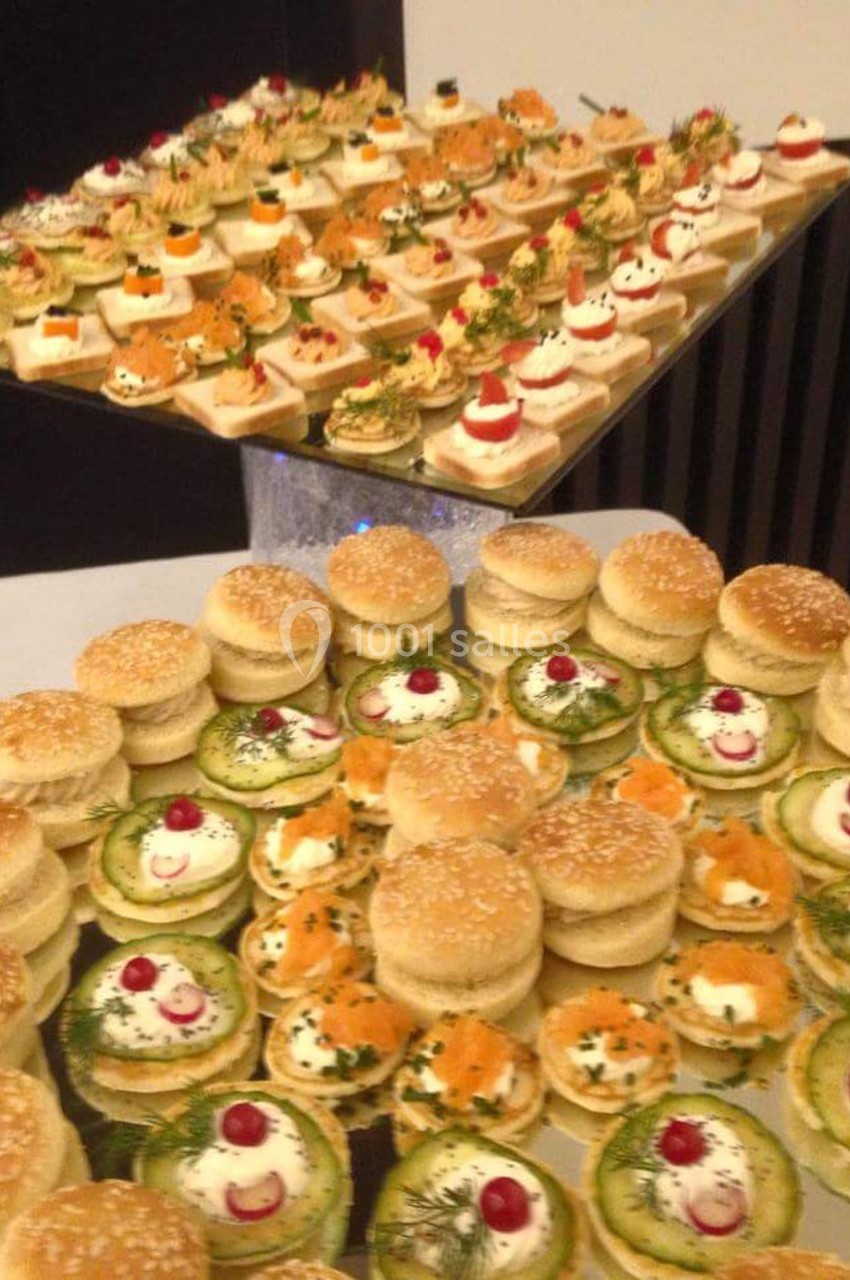 Plateaux de bouchées apéritives variées avec mini-sandwichs, tartelettes salées et canapés décorés.