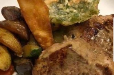 Assiette contenant un morceau de viande avec sauce, légumes rôtis, chips croustillante et garniture verte.