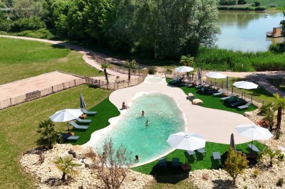 Espace extérieur avec fauteuils en bois, table ronde, et un van rétro bleu stationné en arrière-plan.
