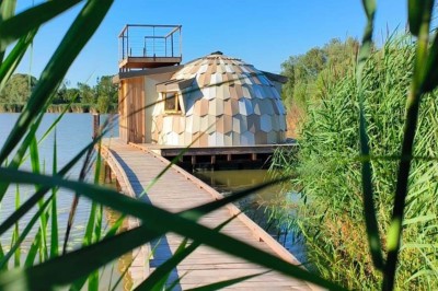 Espace extérieur avec fauteuils en bois, table ronde, et un van rétro bleu stationné en arrière-plan.