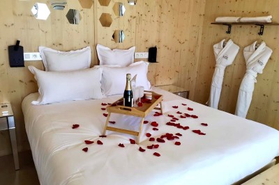 Espace extérieur avec fauteuils en bois, table ronde, et un van rétro bleu stationné en arrière-plan.