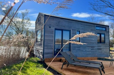 Espace extérieur avec fauteuils en bois, table ronde, et un van rétro bleu stationné en arrière-plan.