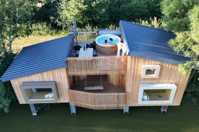 Espace extérieur avec fauteuils en bois, table ronde, et un van rétro bleu stationné en arrière-plan.