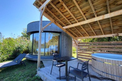 Espace extérieur avec fauteuils en bois, table ronde, et un van rétro bleu stationné en arrière-plan.