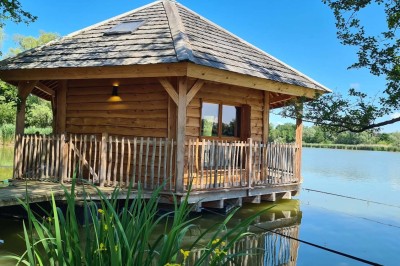 Espace extérieur avec fauteuils en bois, table ronde, et un van rétro bleu stationné en arrière-plan.