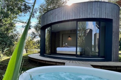 Espace extérieur avec fauteuils en bois, table ronde, et un van rétro bleu stationné en arrière-plan.