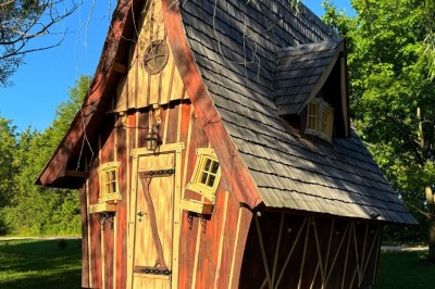 Espace extérieur avec fauteuils en bois, table ronde, et un van rétro bleu stationné en arrière-plan.