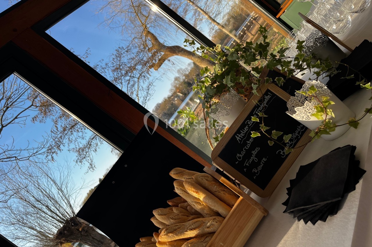 Panier de baguettes sur une table près d'une baie vitrée avec vue sur des arbres et un paysage extérieur ensoleillé.