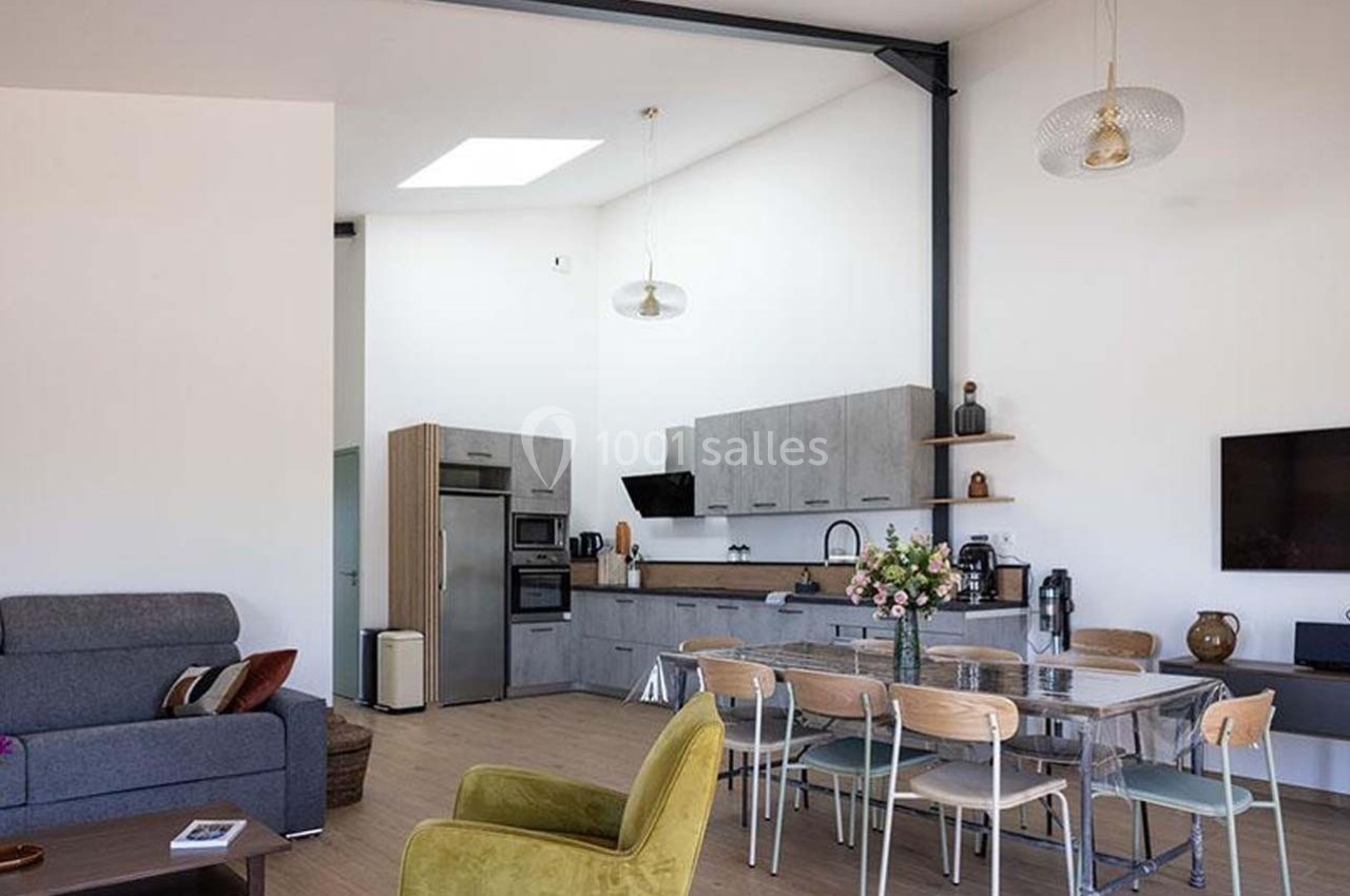 Salle à manger et cuisine ouverte modernes avec table en verre, chaises en bois, canapé, et décoration minimaliste.