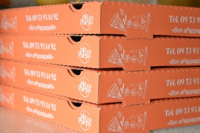Miniature Location salle Voisins-le-Bretonneux (Yvelines) - Pizza Pappa #9 Piles de boîtes à pizza orange empilées, avec un logo, des illustrations et un numéro de téléphone imprimés.