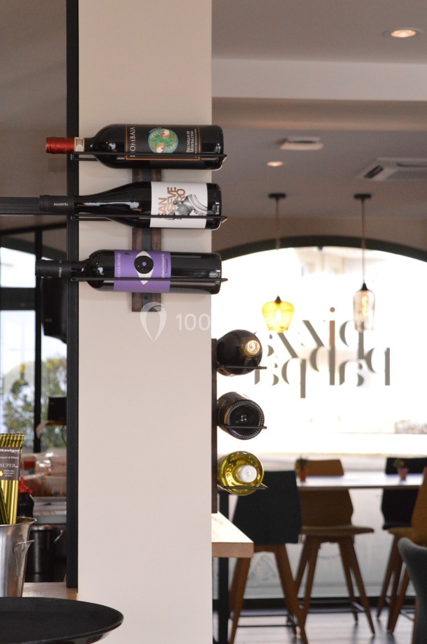 Bouteilles de vin disposées horizontalement sur un support mural dans un intérieur de restaurant moderne.