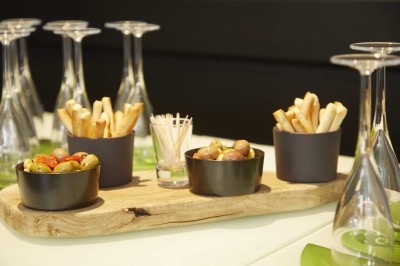 Feuilles vertes dans un vase doré sur une étagère près d'une fenêtre donnant sur une rue urbaine avec bâtiments et grue.