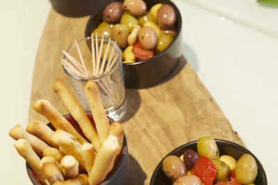 Feuilles vertes dans un vase doré sur une étagère près d'une fenêtre donnant sur une rue urbaine avec bâtiments et grue.
