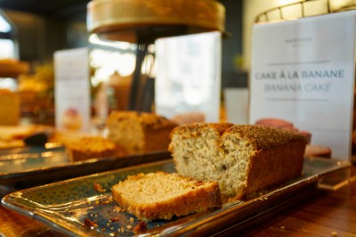 Feuilles vertes dans un vase doré sur une étagère près d'une fenêtre donnant sur une rue urbaine avec bâtiments et grue.