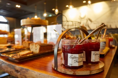 Feuilles vertes dans un vase doré sur une étagère près d'une fenêtre donnant sur une rue urbaine avec bâtiments et grue.