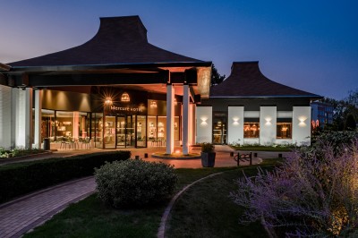 Salle de conférence avec des rangées de chaises colorées face à un écran de projection allumé.