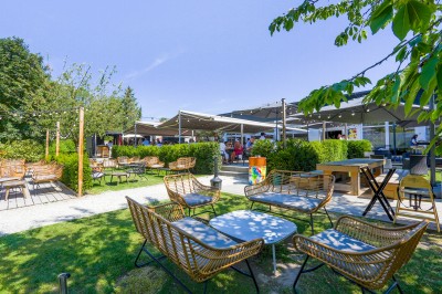 Salle de conférence avec des rangées de chaises colorées face à un écran de projection allumé.