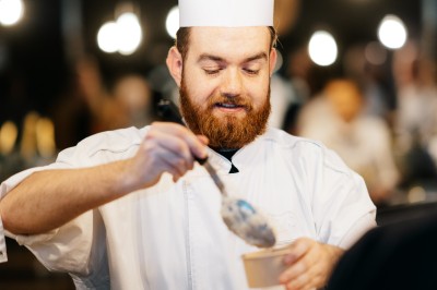 Salle de conférence avec des rangées de chaises colorées face à un écran de projection allumé.