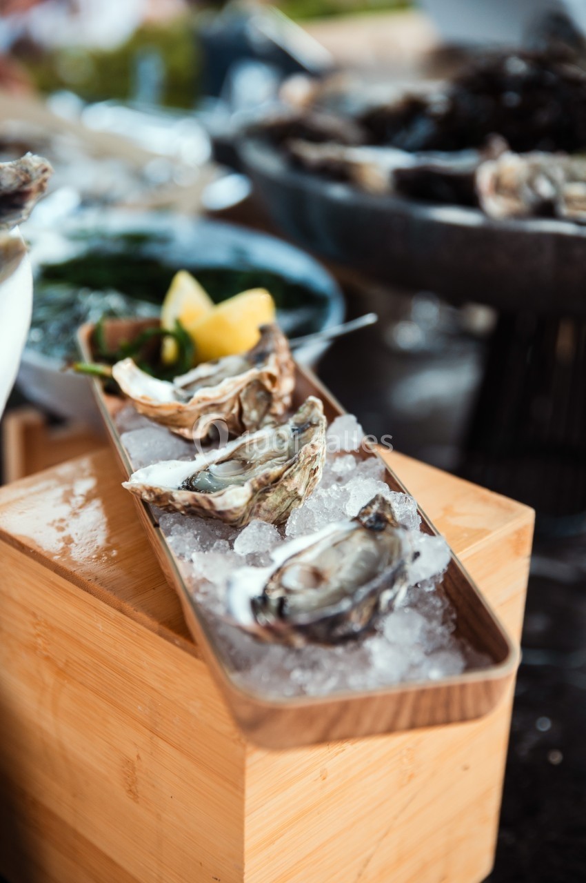 Huîtres fraîches servies sur un lit de glace avec des quartiers de citron en arrière-plan.