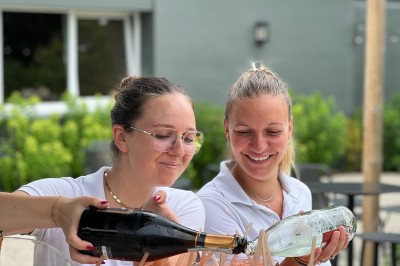 Salle de conférence avec des rangées de chaises colorées face à un écran de projection allumé.